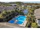 Aerial view of a community pool and jacuzzi surrounded by condos, palm trees, and a pond at 1714 Pine Ridge Rd, Sanford, FL 32773