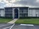 Condo with gray stucco, green bushes, screened balconies on two floors, and a walkway leading to the entrance stairs at 1714 Pine Ridge Rd, Sanford, FL 32773