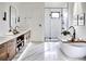 Luxurious bathroom with a freestanding tub, a glass-enclosed shower, marble flooring, and wooden double vanity with storage at 1917 Geigel Ave, Orlando, FL 32806