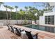 Relaxing poolside with modern lounge chairs on a wooden deck surrounded by manicured palm trees and lush landscaping at 229 Alexander Pl, Winter Park, FL 32789