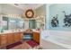 Bright bathroom with a tub, double sink, and a large mirror at 25221 Quail Croft Pl, Leesburg, FL 34748
