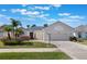 Charming home with a lush front yard, featuring mature palms and well-maintained landscaping and a paved driveway at 25221 Quail Croft Pl, Leesburg, FL 34748