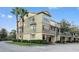 View of a three-story stucco townhome with mature landscaping and a two-car garage at 2604 Grand Central Pkwy # 12, Orlando, FL 32839