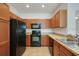 Kitchen featuring wood cabinetry, black appliances, tile floors, and laminate countertops at 2604 Grand Central Pkwy # 12, Orlando, FL 32839