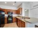 Kitchen featuring wood cabinetry, black appliances, tile floors, and breakfast bar at 2604 Grand Central Pkwy # 12, Orlando, FL 32839