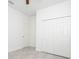 Bright bedroom with white walls and gray tiled floors, featuring a closet with bi-fold doors and a separate entry door at 2765 Sw 140Th Pl, Ocala, FL 34473