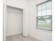 Bedroom closet with bi-fold doors open, showing shelves and view of neighborhood through window with blinds at 2765 Sw 140Th Pl, Ocala, FL 34473