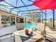 Relaxing screened-in pool area with comfortable seating, a red umbrella, and a scenic view of the backyard at 2805 Ponkan Meadow Dr, Apopka, FL 32712