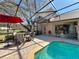 Outdoor patio with a red umbrella, seating, and view of the pool with a screened enclosure at 2805 Ponkan Meadow Dr, Apopka, FL 32712