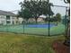 Community tennis court surrounded by a secure fence and lush green landscaping at 2836 Club Cortile Cir, Kissimmee, FL 34746