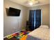 Cozy bedroom featuring a bed, black curtains, and a TV on the wall with dark floors at 3651 N Goldenrod Rd # 210, Winter Park, FL 32792