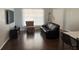 Comfortable living room with dark wood floors, black sofa, TV, and patterned chair at 3651 N Goldenrod Rd # 210, Winter Park, FL 32792