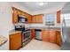 Functional kitchen featuring stainless steel appliances, granite countertops, and wood cabinets with a bright window at 3967 Campfire Way, Casselberry, FL 32707