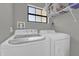 Bright laundry room featuring an Insignia washer/dryer set and storage shelving at 4521 Jim Glenn Dr, Orlando, FL 32808