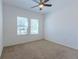 Simple carpeted bedroom featuring two bright windows, a ceiling fan, and neutral wall color at 455 Eaglecrest Dr, Haines City, FL 33844