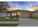 Charming single-story home featuring a two-car garage, landscaped yard, and inviting front entrance at sunset at 455 Eaglecrest Dr, Haines City, FL 33844
