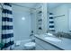 Bright bathroom featuring a shower-tub combination with a blue striped shower curtain and neutral-toned walls at 561 Pebble Beach Dr, Davenport, FL 33896