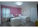Charming bedroom features twin beds with vibrant pink accents creating a playful space for relaxation and rest at 561 Pebble Beach Dr, Davenport, FL 33896