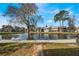 Scenic community view of the pond and sidewalk lined with several condo units and mature trees at 5842 Peregrine Ave # C01, Orlando, FL 32819