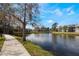 Scenic community view of the pond and sidewalk lined with several condo units on a sunny day at 5842 Peregrine Ave # C01, Orlando, FL 32819