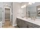 Bathroom with double sinks, gray cabinets, a walk-in closet, and a glass-enclosed shower at 6319 Dew Drop Loop, St Cloud, FL 34771