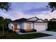 New construction of a one-story home with red entry door, white stucco, stone accents and an attached two-car garage at 6634 Lullaby Way, Mascotte, FL 34753