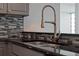 Close-up of kitchen sink featuring stainless steel fixtures, granite countertops, and modern tile backsplash at 101 S Eola Dr # 1001, Orlando, FL 32801