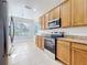 Well-lit kitchen with wood cabinets, stainless steel appliances, and tile flooring at 1121 Magnolia Blossom Ct, Apopka, FL 32712