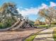 Community playground area with slides surrounded by mature trees and a walkway at 1121 Magnolia Blossom Ct, Apopka, FL 32712