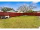 Backyard featuring a large grassy area with a red fence and mature trees at 1201 City Park Ave, Orlando, FL 32808