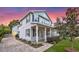 Charming two-story home with a front porch, manicured lawn, and a brick driveway at dusk at 149 E Muriel St, Orlando, FL 32806