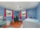 Bedroom featuring blue walls, ceiling fan, two windows with red drapes, and hard wood floors at 1503 Wisconsin Ave, St Cloud, FL 34769