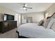 A sunlit bedroom with a dresser, a full-length mirror, patterned bedding, and a ceiling fan at 1546 Park Leah Cir, Apopka, FL 32712