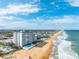 Aerial view featuring oceanfront condo, sandy beach, lush landscaping, and inviting pool area at 1575 Ocean Shore Blvd # 306, Ormond Beach, FL 32176