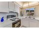 Cozy kitchen featuring an electric range oven, white cabinetry, and double sink at 1575 Ocean Shore Blvd # 306, Ormond Beach, FL 32176