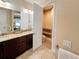 Bathroom vanity featuring double sinks and dark cabinetry, leading to toilet room at 172 Balmy Coast Rd, Groveland, FL 34736