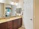 Bathroom vanity with dark cabinetry and granite countertop, reflecting a bedroom at 172 Balmy Coast Rd, Groveland, FL 34736