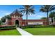 Entrance to the Trilogy community featuring mature palm trees, vibrant flowers, and a well-maintained lawn at 172 Balmy Coast Rd, Groveland, FL 34736