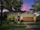 Inviting single-Gathering home with lush landscaping, a brick driveway, solar panels, and an attached two-car garage at twilight at 172 Balmy Coast Rd, Groveland, FL 34736