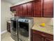 Laundry room with front load washer and dryer, granite countertops, and brown cabinetry at 172 Balmy Coast Rd, Groveland, FL 34736