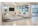 This staged living room features three white arm chairs, a glass table, a TV, and lots of natural light at 172 Balmy Coast Rd, Groveland, FL 34736