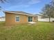 Spacious backyard with green grass and a sliding glass door leading to the home at 240 Whispering Pines Way, Davenport, FL 33837