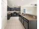 Well-lit kitchen featuring dark cabinets, a peninsula with a stainless steel sink, and modern appliances at 240 Whispering Pines Way, Davenport, FL 33837