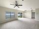 Spacious living room with plush carpeting, ceiling fan, light fixture, and large windows at 240 Whispering Pines Way, Davenport, FL 33837