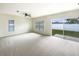 Spacious living room featuring neutral carpet, a ceiling fan, and a sliding glass door to the backyard at 240 Whispering Pines Way, Davenport, FL 33837