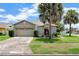 Charming single story home with an attached garage, well manicured bushes, and green grass at 3221 White Dove Ln, Kissimmee, FL 34746