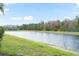 Community pond view with green shoreline and building in the background on a clear day at 3575 Victoria Pines Dr # 276, Orlando, FL 32829