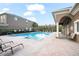 Community pool with lounge chairs and tables surrounded by a building on a sunny day at 3575 Victoria Pines Dr # 276, Orlando, FL 32829