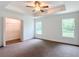 Comfortable bedroom featuring tray ceiling, neutral carpet flooring, closet and ensuite access at 4790 Sw 166Th Loop, Ocala, FL 34473