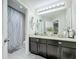 Bathroom with double sink vanity, granite counters, decorative wall accents and shower at 4820 Battaglia Blvd, St Cloud, FL 34769